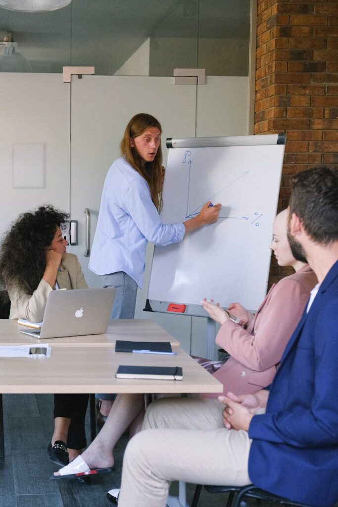 employee drawing graph on flipchart during meeting in workspace